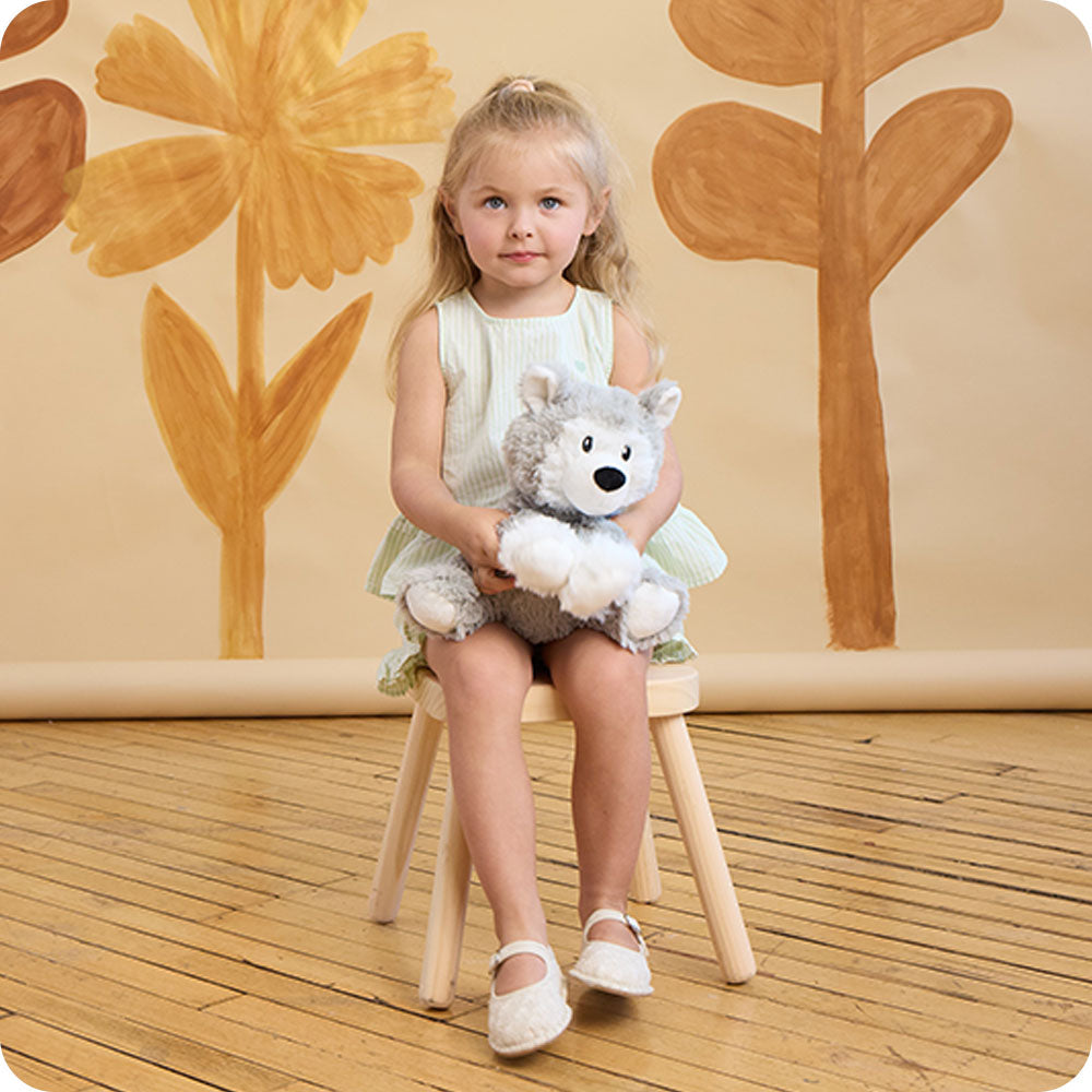 Image 104: girl holding a warmies husky stuffed animal